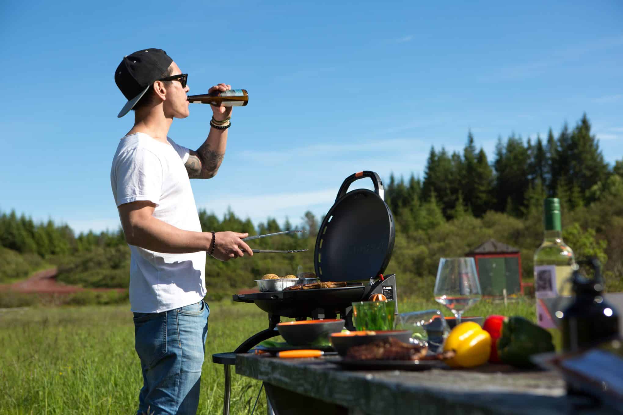 man outside barbecueing and drinkin beer