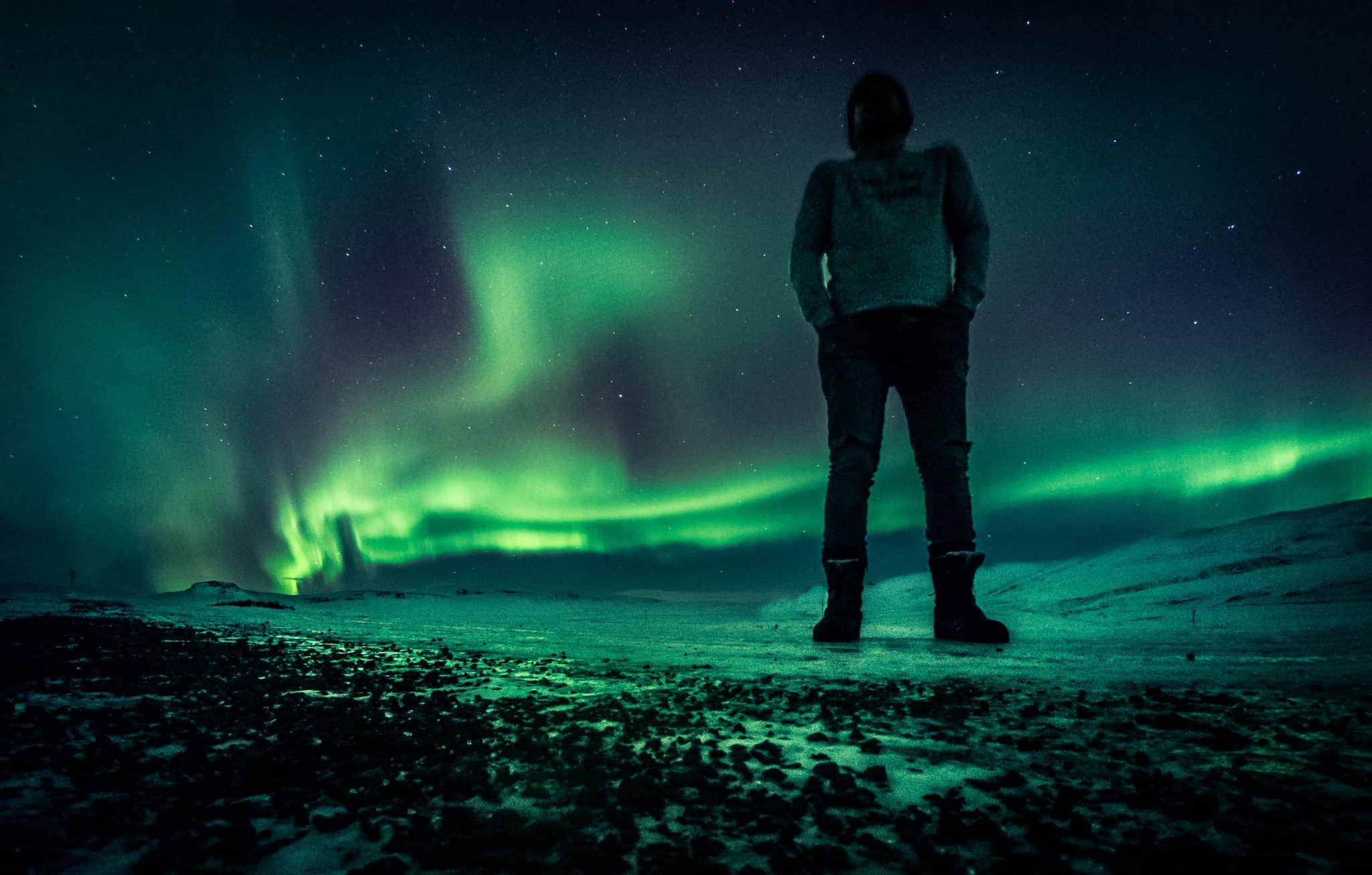 man standing outside under the Norhern Lights