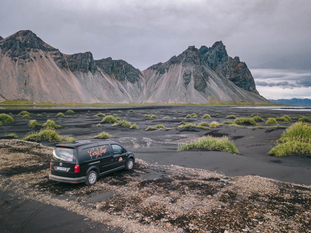 A cozy camper van drives through a scenic valley in Iceland