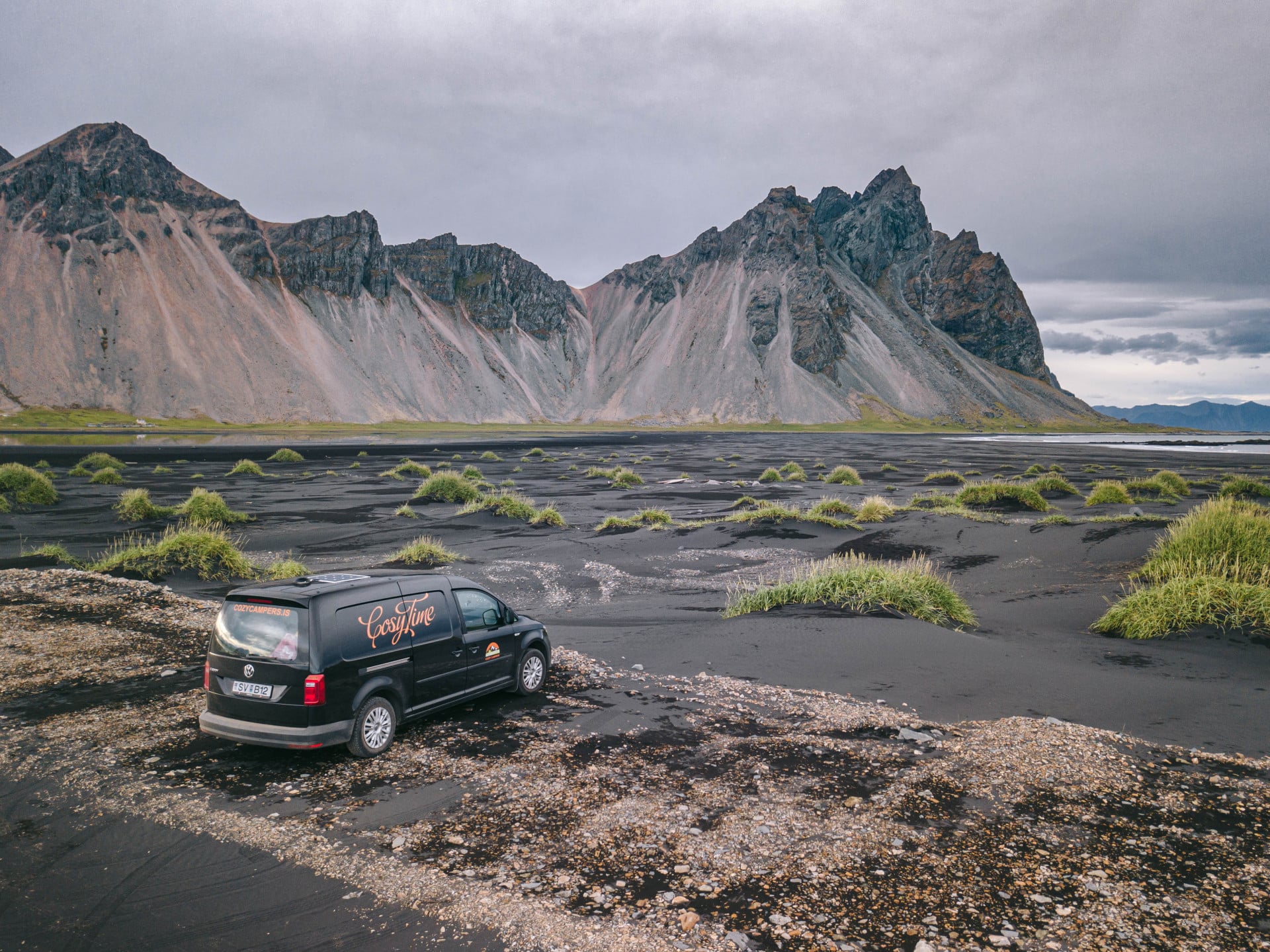 A cozy camper van drives through a scenic valley in Iceland