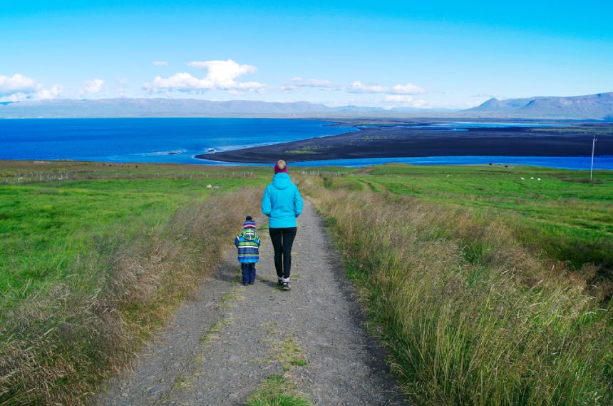 A parent and child walk down a path in Iceland.