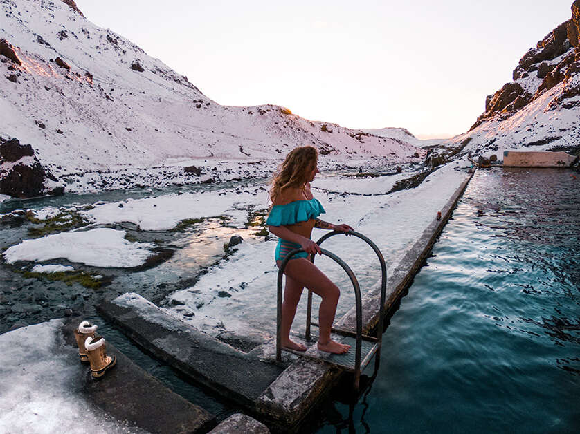 A woman stepping into a geothermal pool in Iceland