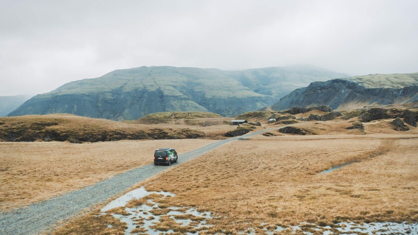 A Cozy Camper van nestled between brown mountains and hills in the distance.